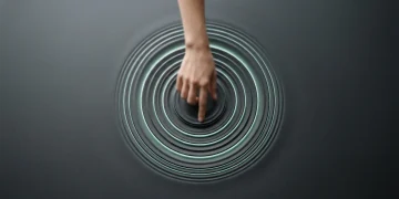 A hand creating ripples on a dark, smooth surface, subtly lit with a cool green glow, symbolizing global cultural influence and its far-reaching effects on modern living trends.