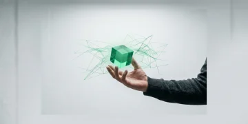 A person's hands engaging with an emerald green holographic projection of intertwined data networks, symbolizing the convergence of AI, 5G, and blockchain.